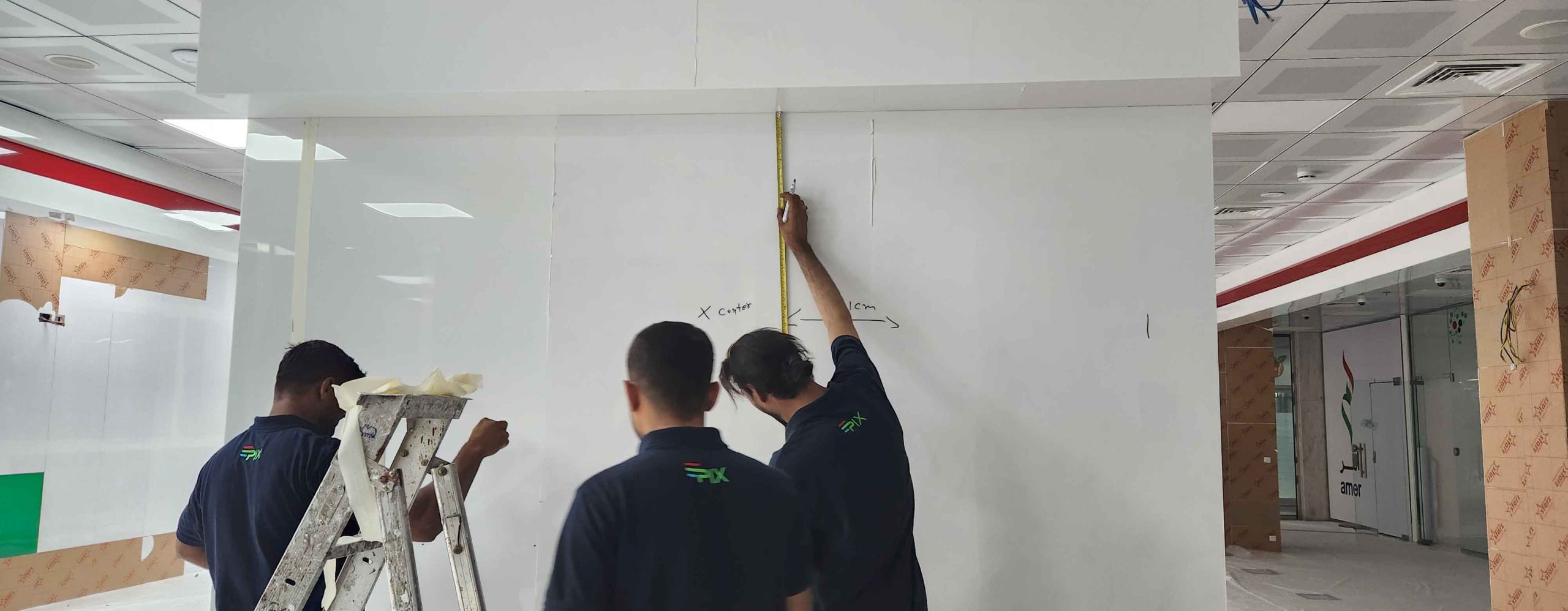 Epix technicians measuring the reception wall at Amer Center before LED screen installation